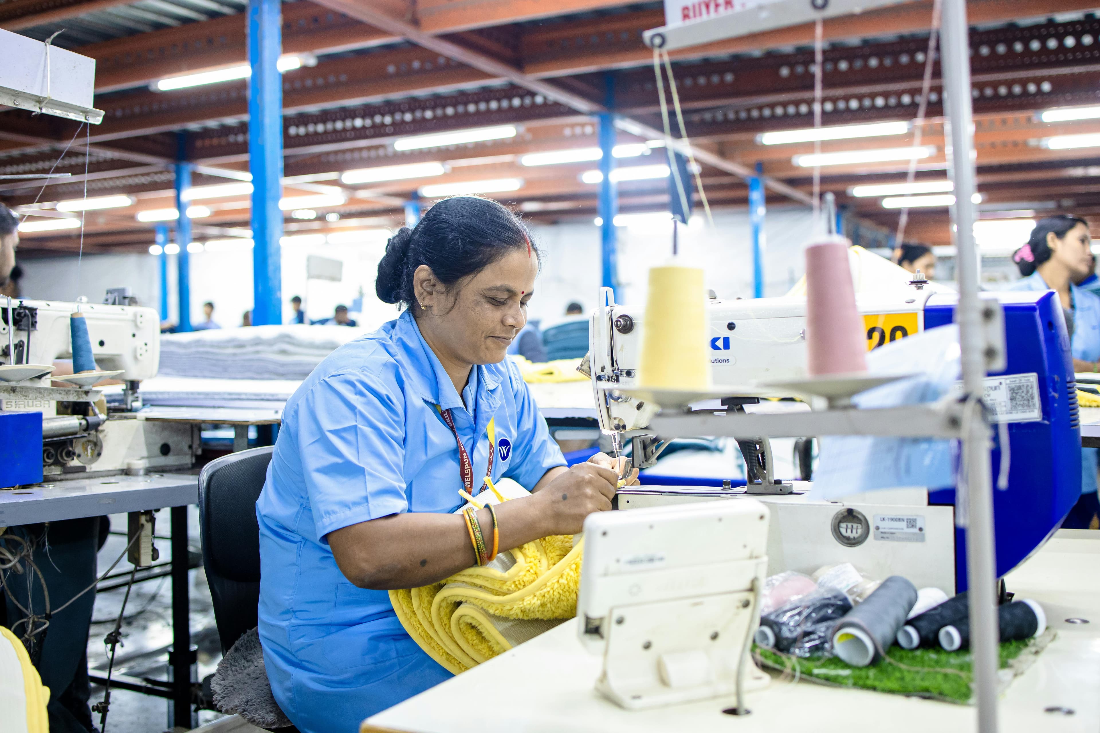 Technician operating an industrial sewing machine on a bright factory floor